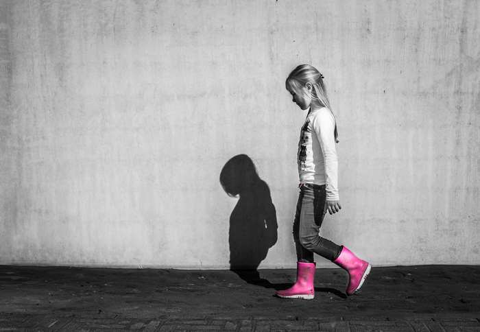 Girl in pink boots walking by a wall