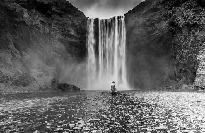 Person standing before Skogafoss waterfall in Iceland