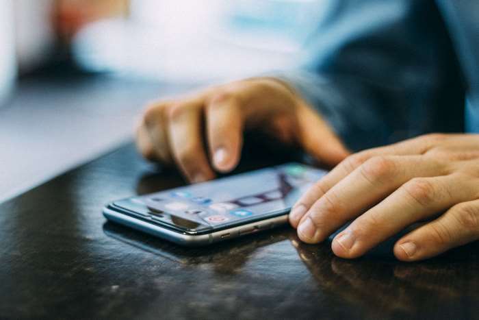 Man's hands using a smartphone on a table