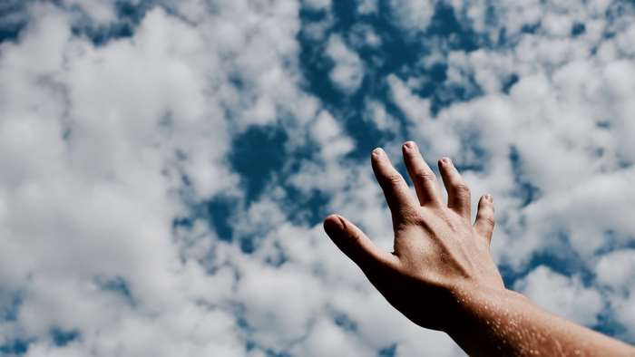 Hand Reaching Towards Clouds in Sky 4K