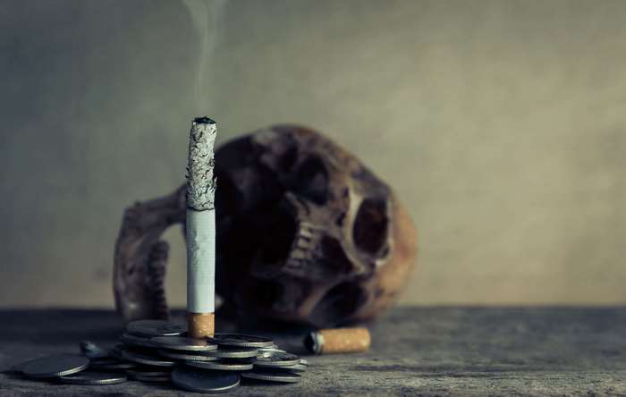 Burning cigarette on coins with skull, 4K