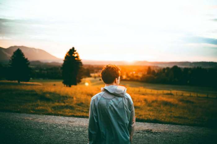 Man looking at sunset over mountains and trees 4K
