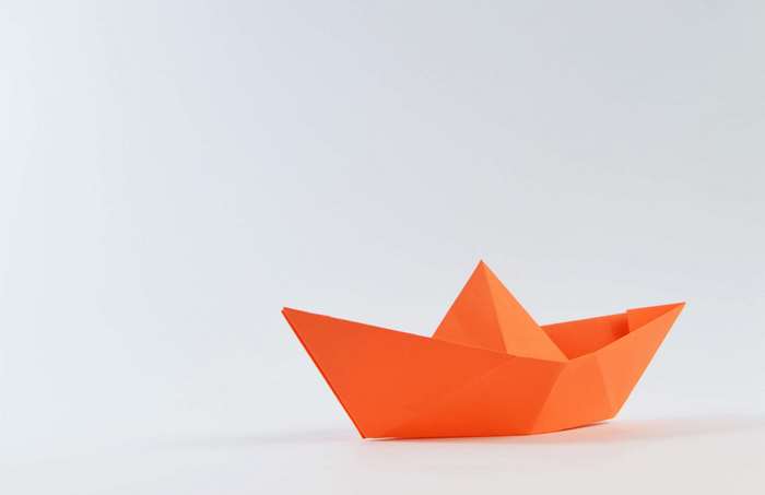 Orange origami boat on a white background