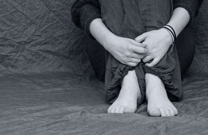 Person sitting alone with knees pulled to chest