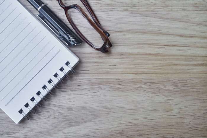 Notebook, Pen, and Eyeglasses on Wooden Table