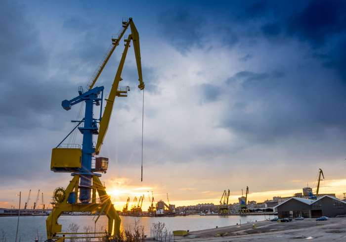 Industrial cranes at a port during sunset