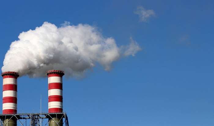 Two industrial smokestacks emitting smoke