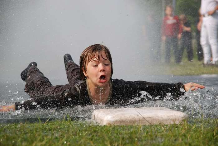 Child sliding through water on grass