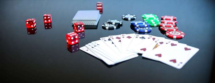 Playing cards, dice, and poker chips on a reflective surface
