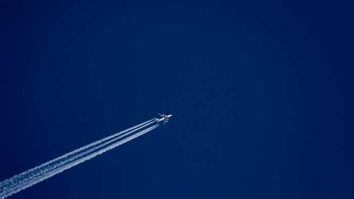 Airplane flying in a clear blue sky with contrails