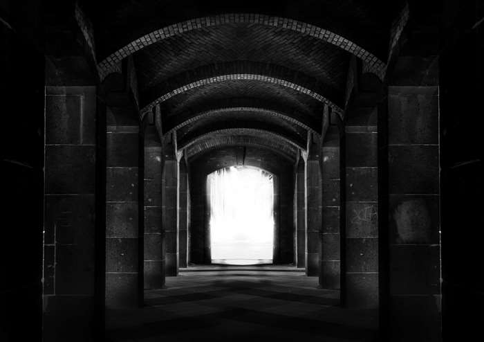 Dark arched hallway with bright light at the end