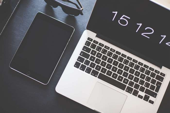 Apple MacBook, iPad, and sunglasses on a desk