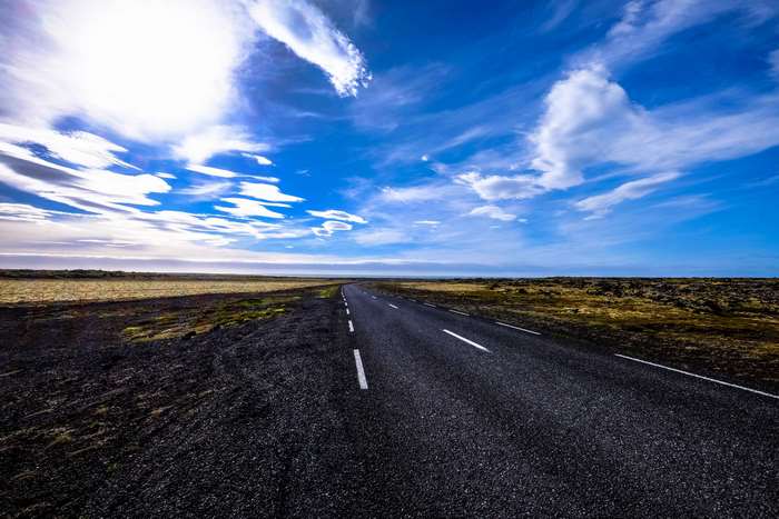 Asphalt road through a barren landscape under a cloudy sky