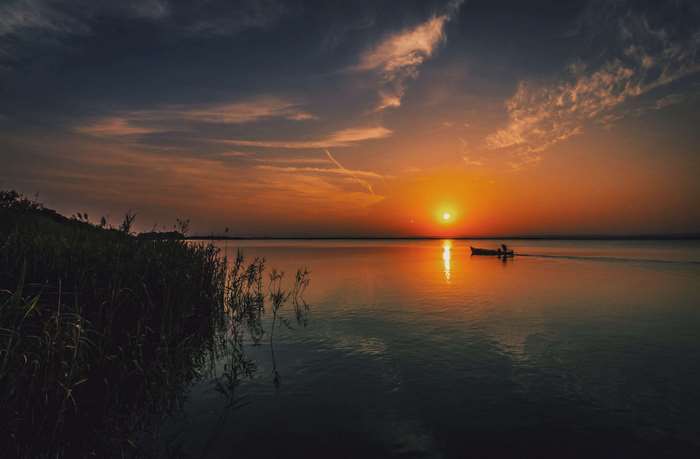 Sunset over a calm lake with a boat