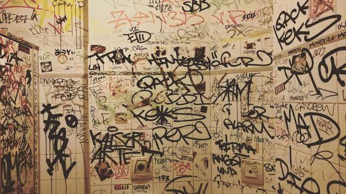 Graffiti-covered bathroom stalls with toilets