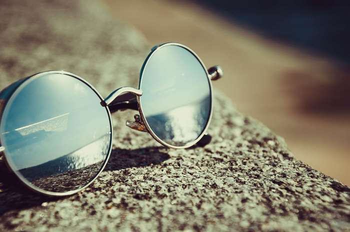 Round sunglasses with reflective lenses on a rock