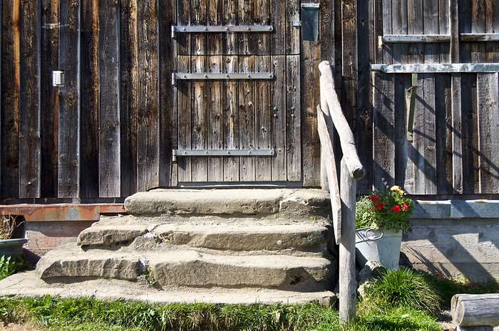 Rustic wooden cabin entrance with stone steps and railing