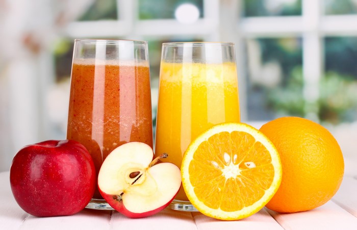 Two glasses of juice with apples and oranges