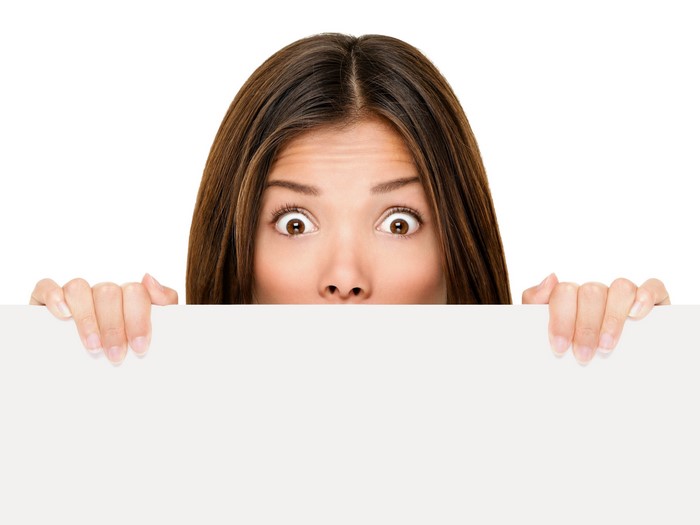 Woman peeking over a white poster