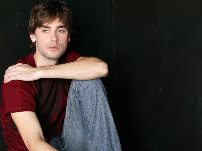 Drew Fuller sitting against a dark background