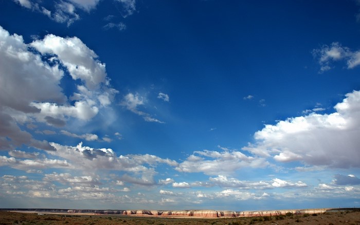 Vast blue sky with scattered clouds over a desert landscape