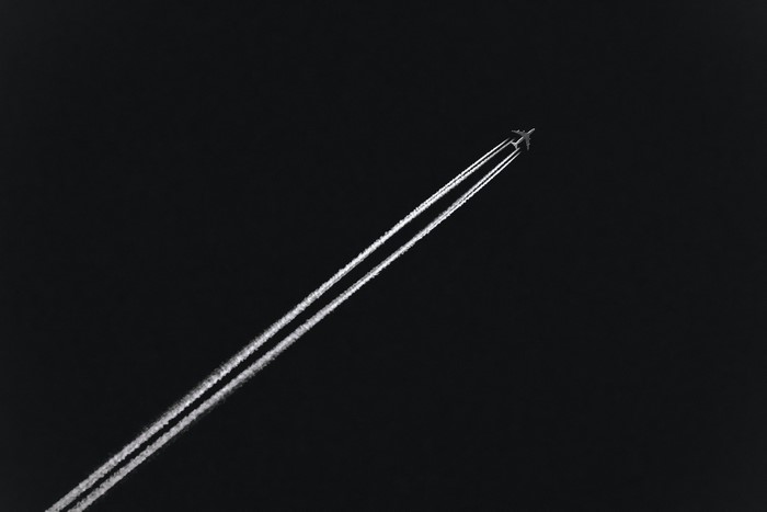 Airplane leaving contrails in the dark sky