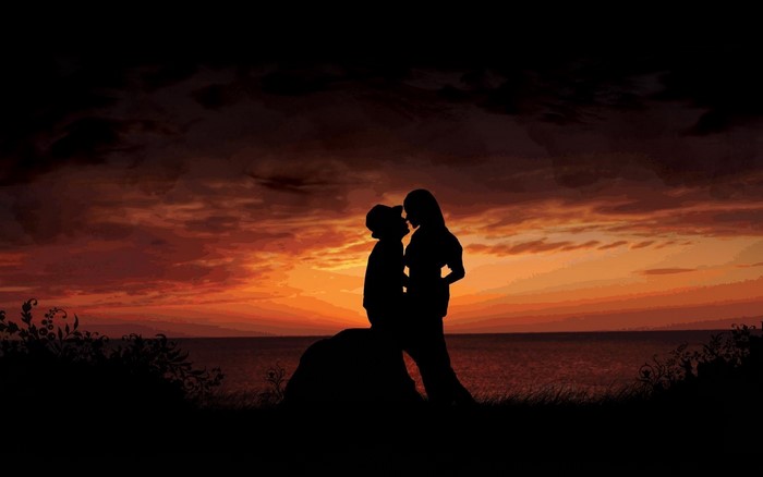 Couple embracing on a rock at sunset