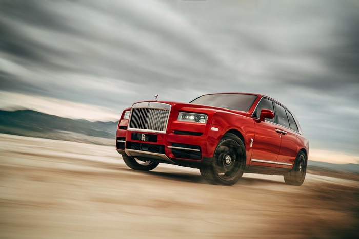 Red Rolls-Royce Cullinan driving on a dirt road