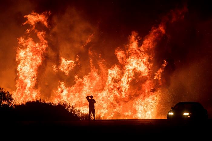 Man watching a massive wildfire at night