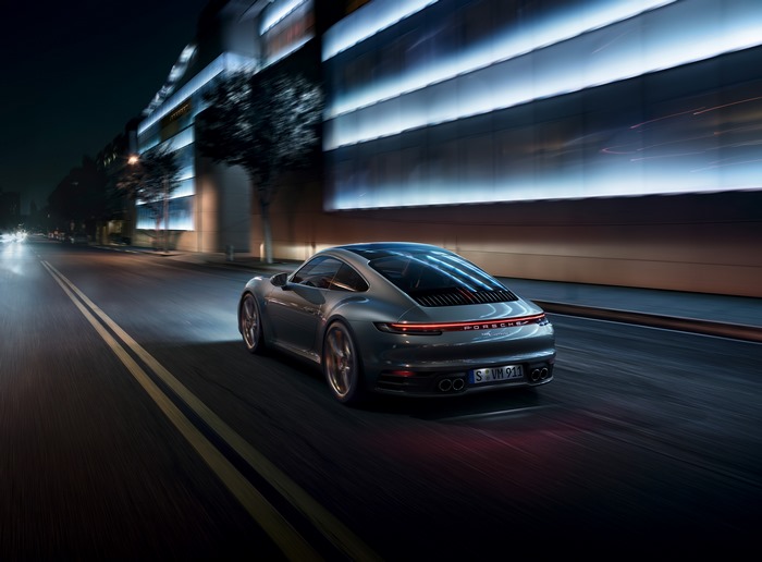 Porsche 911 driving on a city street at night