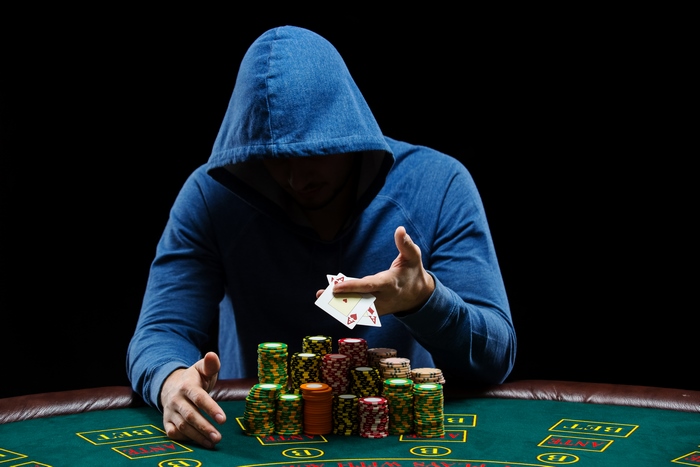 Man in hoodie playing poker with chips and cards