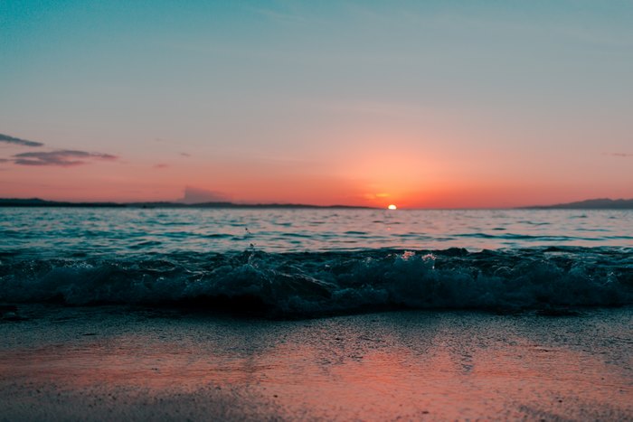 Sunset over the ocean with waves on the shore