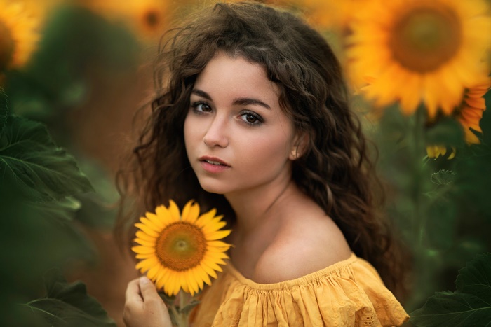 Girl with sunflower in a field of sunflowers