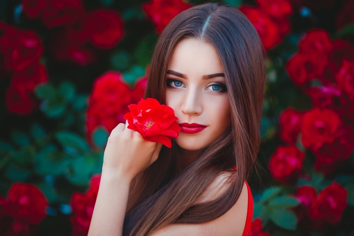 Woman with long brown hair holding a red rose