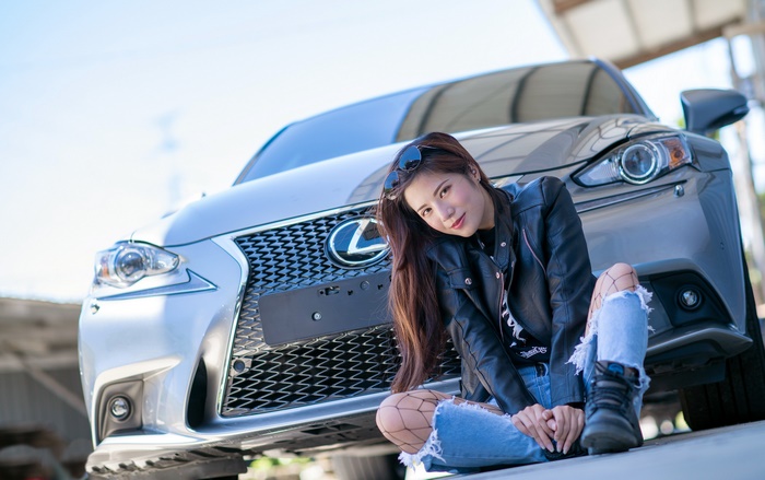 Woman in leather jacket posing with Lexus car