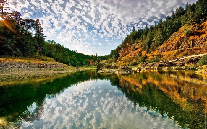 River flowing through a forested canyon with rocky hills