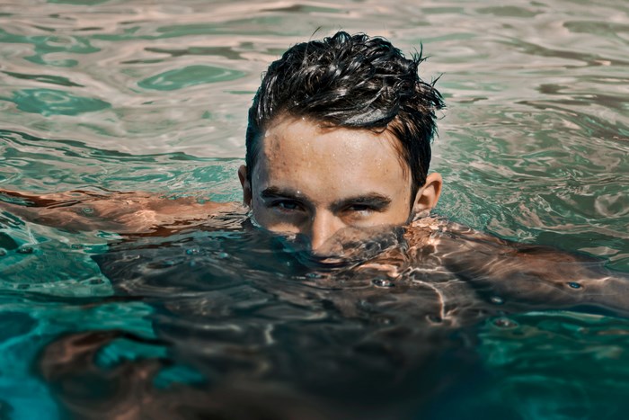 Man swimming in water, looking at camera