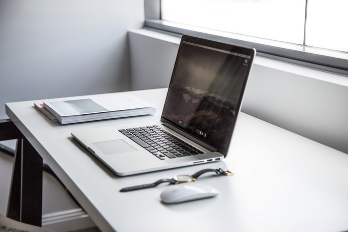 MacBook Pro on a white desk with books and watch