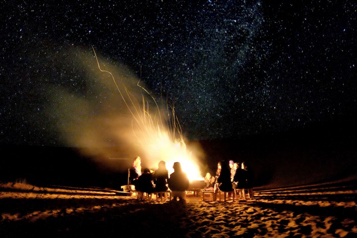 People around a campfire under a starry desert sky