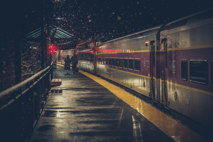 Couple walking at a snowy train station at night