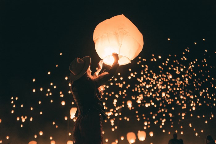 Woman releasing a sky lantern at a festival at night