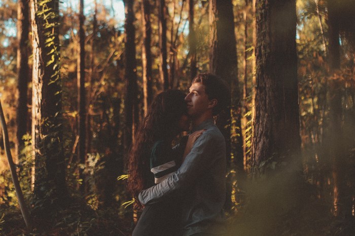 Couple hugging in a forest during sunset