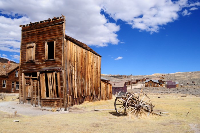 Abandoned wooden buildings in a ghost town under a blue sky