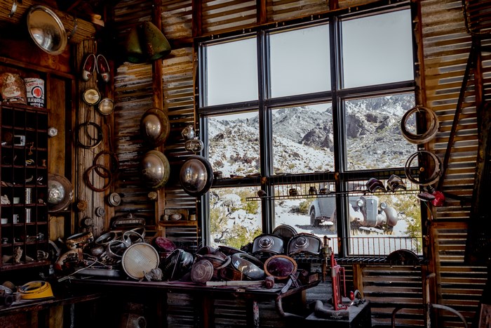 Vintage auto parts workshop with desert mountain view