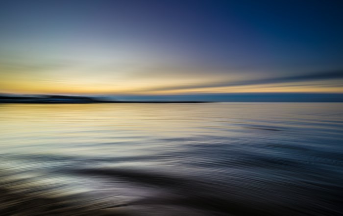 Long exposure seascape with yellow and blue sky