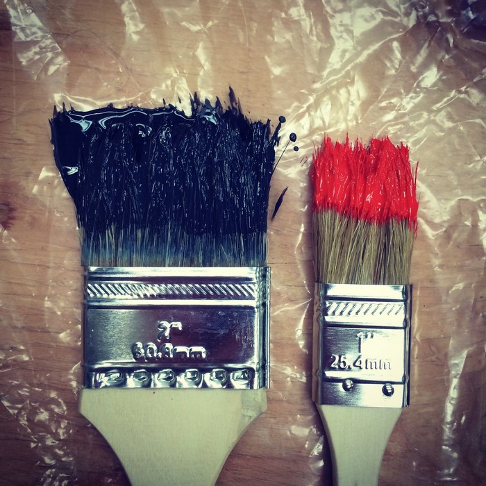 Two paint brushes with black and red paint