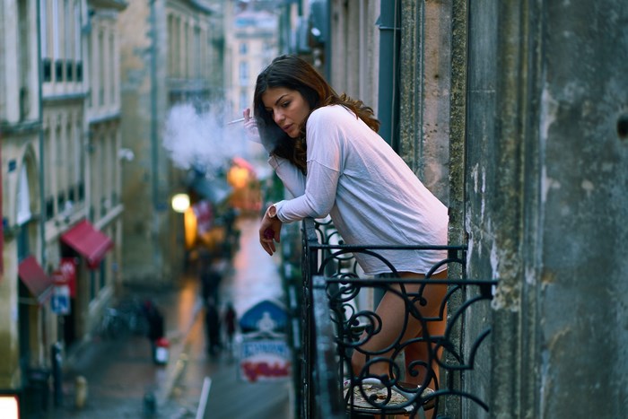 Woman smoking on a balcony in Bordeaux, France