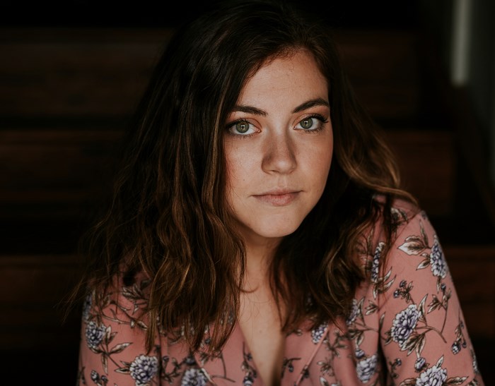 Woman with green eyes wearing a floral shirt on stairs