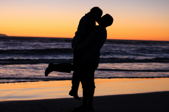 Couple kissing on a beach at sunset