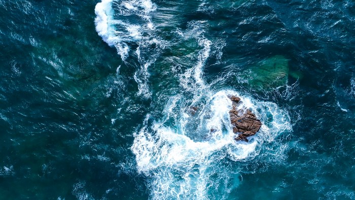 Aerial view of rough ocean waves crashing on rocks